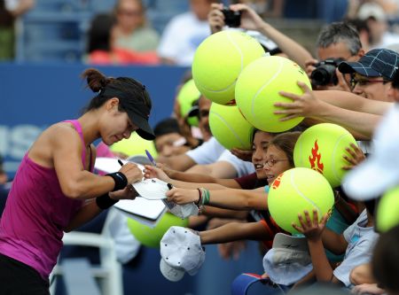 Li Na of China signs for fans after her victory over Francesca Schiavone of Italy at women's singles fourth round match of the U.S. Open tennis tournament in New York, the U.S., Sept. 6, 2009.(Xinhua/Shen Hong)