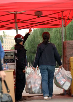 A policeman tests the temperature of a woman at an entrance to the university town in Langfang, northern China's Hebei Province, Sept. 7, 2009.[Gong Zhihong/Xinhua]