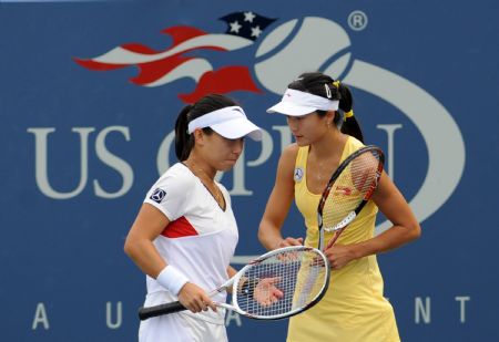 Yan Zi (R) of China whispers to her partner Zheng Jie during the women's doubles third round match against Daniela Hantuchova of Slovakia and Ai Sugiyama of Japan at the U.S. Open tennis tournament in New York, Sept. 7, 2009. (Xinhua/Shen Hong)