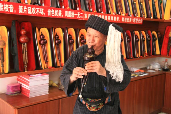 A folk instrument player performs in his own store in the Fenghuang Ancient Town in China's Hunan Province on September 3, 2009. [Photo: CRIENGLISH.com]