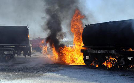 Pakistani paramilitary soldiers stand behind burning NATO oil supply tankers on the outskirts of Quetta September 8, 2009. [Xinhua/AFP]