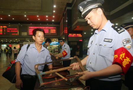 A policeman conducts security check on a passenger's hand luggage at the Hangzhou Railway Station, in east China's Zhejiang province, Sept. 8, 2009. [Xinhua]