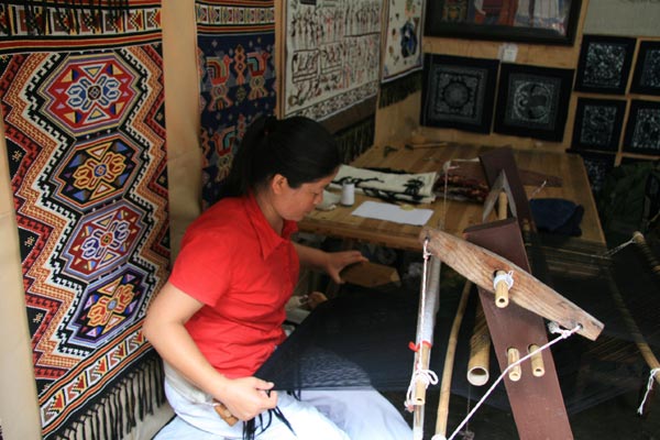 Ye Shuiyun demonstrates how to weave Tujia ethnic brocade. [Photo: CRIENGLISH.com/Duan Xuelian]