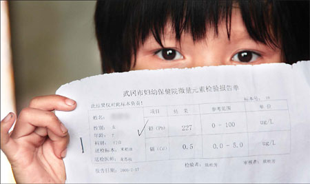 A 7-year-old girl from Hengjiang village in Wugang, Hunan province, holds the results that show she has 227 mcg/l in her system.[