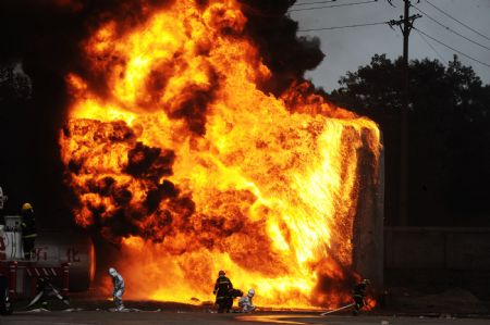 Firefighters react to the fire of an oil tank during a security and rescue drill in Changsha, capital of central China's Hunan Province Sept. 9, 2009.(Xinhua/Long Hongtao)