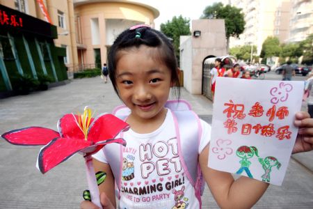 Wang Tian'en, a pupil at Meilong Central School, shows her DIY present for her teacher in Shanghai, east China, Sept. 10, 2009.[Liu Ying/Xinhua]