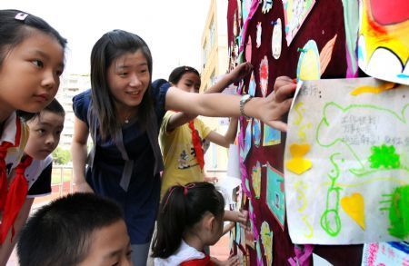 Pupils and teachers at Meilong Central School visit the wall covered with special cards made by pupils for teachers in Shanghai, east China, Sept. 10, 2009. It was Teachers' Day on Thursday and students sent sweet gifts to their hardworking teachers. [Liu Ying/Xinhua]