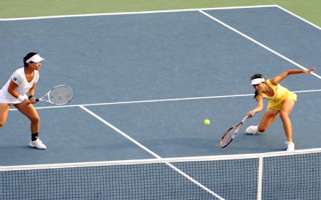 Yan Zi of China (R) returns a shot as her compatriot Zheng Jie watches during the women's doubles quarter final against Venus and Serena Williams of the US at the U.S. Open tennis tournament in New York, the U.S., Sept. 9, 2009.(Xinhua/Shen Hong)
