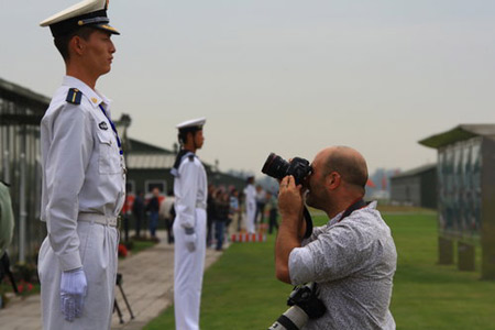 A foreign media staffer takes photos of a soldier at Beijing's Military Parade Village Thursday. [CFP]