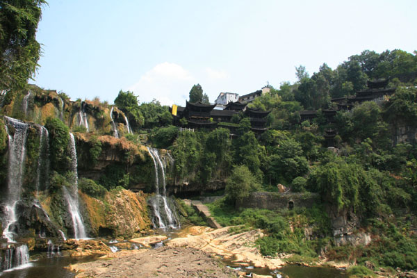 A waterfall hangs on a low mountain at the entrance to Hibiscus Town. [Photo:CRIENGLISH.com/Duan Xuelian]