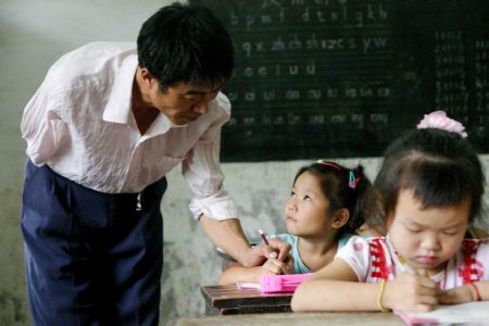 Shao Jun (L) gives a class to pupils at Dongshan Primary School in Sanbing Township of Chaohu City, east China's Anhui Province, Sept. 8, 2009. Shao, 42 years old, lost his right arm during an accident at the age of 19. He started teaching at Dongshan Primary School in 1998 and spent 11 years there. As high-grade pupils were gradually transferred to downtown schools, there is one class in the school with only eight pupils. (Xinhua)