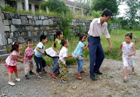 Shao Jun (R2) plays games with pupils at Dongshan Primary School in Sanbing Township of Chaohu City, east China's Anhui Province, Sept. 8, 2009. Shao, 42 years old, lost his right arm during an accident at the age of 19. He started teaching at Dongshan Primary School in 1998 and spent 11 years there. As high-grade pupils were gradually transferred to downtown schools, there is one class in the school with only eight pupils. (Xinhua)