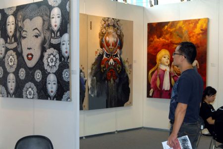 A visitor watches exhibits during the ongoing 13th Shanghai Art Fair, which opens at the Shanghai Mart, in Shanghai, east China, Sept. 9, 2009. 
