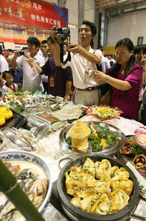 Visitors take pictures during a food festival held in Suzhou, east China's Jiangsu Province, Sept. 12, 2009. The 4th China Suzhou Food Festival, which was also the 1st China 'Su Style' Moon Cake Cultural Festival, was opened at the gymnasium of Xiangcheng District in Suzhou on Saturday. [Hang Xingwei/Xinhua] 