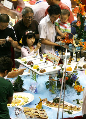 Visitors take pictures during a food festival held in Suzhou, east China's Jiangsu Province, Sept. 12, 2009. The 4th China Suzhou Food Festival, which was also the 1st China 'Su Style' Moon Cake Cultural Festival, was opened at the gymnasium of Xiangcheng District in Suzhou on Saturday. [Hang Xingwei/Xinhua] 