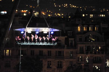 Guests have supper at a new event venue which offers 'Dinner in the Sky' as they are seated around a table that is lifted by a crane above the Tuileries Garden in Paris September 11, 2009.[Xinhua/AFP]