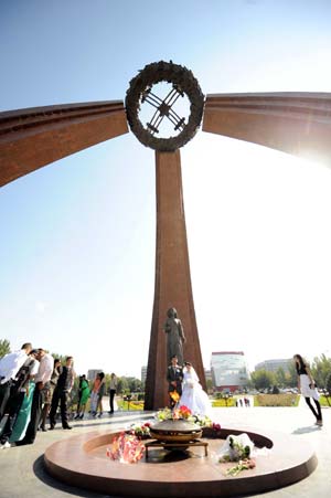 A newly-married couple poses for photos with family members at the Victory Square in Bishkek, capital of Kyrgyzstan, Sept. 12, 2009. It is a tradition for many Kyrgyzstan's newly-married couples to come to the Victory Square to pray for happiness in their life.[Sadat/Xinhua]