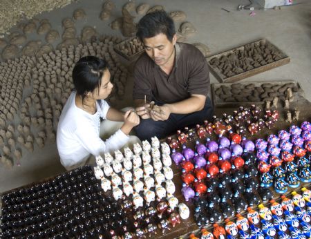 A folk craftsman (R), makes 'Nigugu', a traditional putty-made toy, at Yangjitun Village of Junxian County, central China's Henan Province, Sept. 12, 2009.(Xinhua/Chang Zhongzheng) 