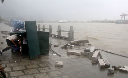 Two pedestrians hide themselves against the gale and rainstorm on the bank as an aftermath of the gales and heavy rains brought by the tropical storm Koppu, at Zhuhai City, south China's Guangdong Province, Sept. 15, 2009. Typhoon Koppu staged a landing Tuesday morning on the coast of southern China's Guangdong Province, bringing about gales and rainstorm with a top precipitation at 148.5 mm in the province. The typhoon, the 15th this year, landed at around 7:00 a.m. at Beidou town of Taishan city, packing up winds of 126 km/hour at its eye, according to the provincial meteorological bureau. (Xinhua/Xi Hu)