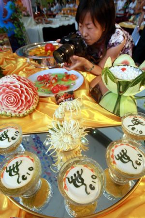 A visitor takes photos of dishes during a cooking competition greeting the 2010 Shanghai World Expo held in Wujiaochang in Yangpu District of Shanghai, east China, Sept. 15, 2009, which attracted chefs from 16 catering companies joining in the competition. [Xinhua]