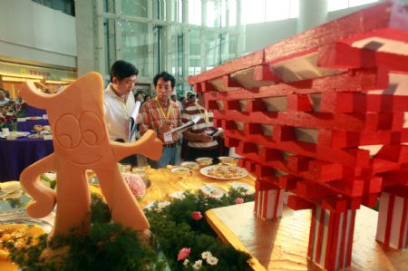 Judges mark dishes during a cooking competition greeting the 2010 Shanghai World Expo held in Wujiaochang in Yangpu District of Shanghai, east China, Sept. 15, 2009, which attracted chefs from 16 catering companies joining in the competition. [Xinhua]