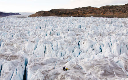 University of Maine glaciologist Gordon Hamilton and graduate student Kristin Schild working on a GPS receiver tracking the flow speed of Helheim Glacier in southeast Greenland last month. Like Greenland's other major glaciers, it accelerated earlier this decade, contributing to the melt of the ice sheet and sea-level rise.