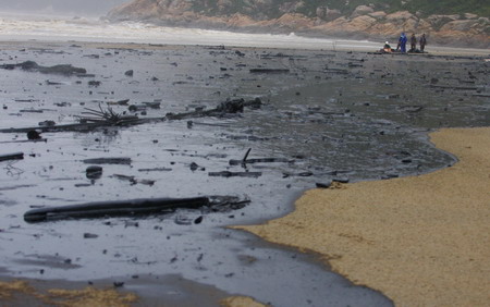 Workers clean up a large patch of oil from a cargo ship that hit the rocks in Zhuhai port, Guangdong province, on September 15, 2009. [Photo: China Daily]