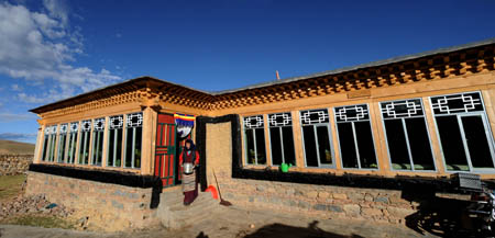 A woman walks out of herdsman Cering Tonzhub's new house in Bangoin County, southwest China's Tibet Autonomous Region, Sept. 15, 2009. Thanks to the government's comfortable housing project in the past 3 years, over a million farmers and herdsmen in Tibet have moved into new houses. (Xinhua/