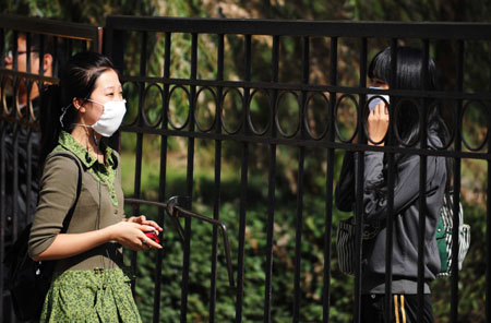 Two students talk at the gate of Heilongjiang University in Harbin, capital of northeast China's Heilongjiang Province, Sept. 16, 2009. Heilongjiang University scheduled to suspend class from 8:00 a.m. on Sept. 16 to Sept. 19 due to the A/H1N1 flu collective outbreak which was confirmed on Sept. 13.