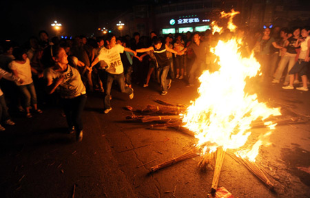 People dance around the bonfire during the torch festival in Xichang, capital of Liangshan Yi autonomous prefecture, Sichuan province, August 15, 2009. The festival is also called the Oriental Valentine's Day as young people approach and court their favored ones during the public dancing and singing. It is one of the nation's top 10 festivities for its minority ethnic groups. [Xinhua] 