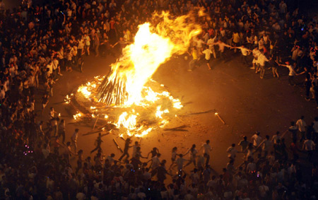 People dance around the bonfire during the torch festival in Xichang, capital of Liangshan Yi autonomous prefecture, Sichuan province, August 15, 2009. [Xinhua] 