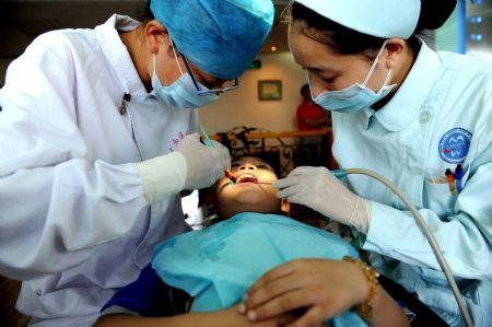 Doctors conducts pit and fissure sealing for a child in Nanning, southwest China's Guangxi Zhuang Autonomous Region, on Sept. 20, 2009.(Xinhua/Zhang Ailin)