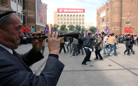 A man plays a musical instrument as residents dance to celebrate the Eid al-Fitr in Urumqi, capital of northwest China's Xinjiang Uygur Autonomous Region, Sept. 21, 2009.(Xinhua/Jiang Wenyao) 