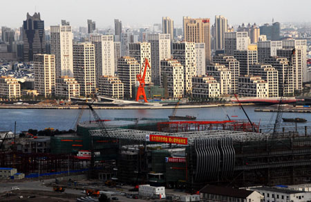 Photo taken on Sept. 20, 2009 shows the World Expo Village (back) under construction in Shanghai, east China. Construction of "one axis and four pavilions", the Axis, China Pavilion, Theme Pavilion, Performing Arts Center and Expo Center, all entered internal construction phase recently. As the landmarks of the Expo Park, "one axis and four pavilions" will become permanent buildings in post-Expo Shanghai.