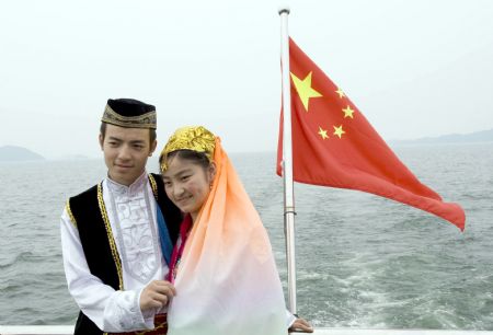 A pair of newlywed pose for photos in front of China's national flag in Qiandaohu Scenic Area of Chun'an County, east China's Zhejiang Province, Sept. 20, 2009.(Xinhua/Zhou Jinyou)