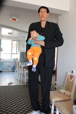 2.36-meters-high Chinese herdsman Bao Xishun, the previous world's tallest man, holds his less than 1-year-old son at home, in Chifeng City, north China's Inner Mongolia Autonomous Region, Sept. 21, 2009. (Xinhua/Li Fu)