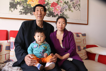 2.36-meters-high Chinese herdsman Bao Xishun, the previous world's tallest man, stays with his wife and son at home, in Chifeng City, north China's Inner Mongolia Autonomous Region, Sept. 21, 2009. (Xinhua/Li Fu)