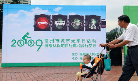 People walk past a poster advocating the idea of the Car-Free Day in Fuzhou, capital of southeast China's Fujian Province, on Sept. 22, 2009. This Tuesday is China's third Car-Free Day and people are encouraged to walk, ride bikes or take buses instead of driving their cars. Jiang Kehong/Xinhua]
