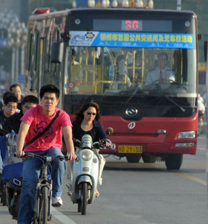 Locals ride bicycles or take buses on a street in Liuzhou, southwest China's Guangxi Zhuang Autonomous Region, Sept. 22, 2009. This Tuesday is China's third Car-Free Day and people are encouraged to walk, ride bikes or take buses instead of driving their cars. [Huang Xiaobang/Xinhua]