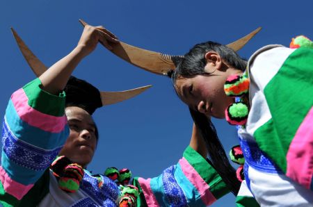 Men of the Miao ethnic group arrange decorations for each other before they perform at a leek flower cultural festival held in Hezhang, southwest China's Guizhou Province, Sept. 22, 2009. The festival opened on Tuesday in Hezhang county that grows wild leek plants of more than 30 square kilometers. (Xinhua)