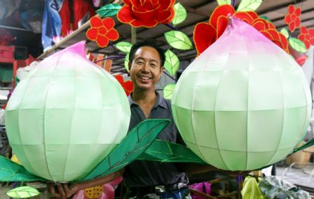 A worker presents newly-finished peach-shaped lanterns at a lantern workshop in Suzhou, east China's Jiangsu Province, Sept. 22, 2009. Various lanterns are geared up at the workshop for the forthcoming Mid-Autumn Festival, which falls on Oct. 3 this year. (Xinhua/Hang Xingwei)