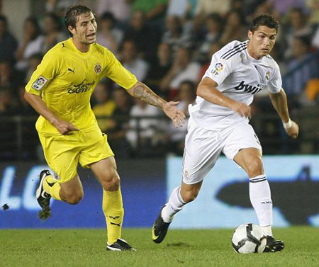 Real Madrid's Cristiano Ronaldo (R) and Villarreal's Sebastian Eguren fight for the ball during their Spanish first division soccer match at the Madrigal Stadium in Villarreal September 23, 2009.