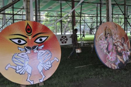 A paint worker walks past boards imprinted with images of Hindu Goddess Durga at a makeshift temple one day ahead of Durga Puja, the biggest religious festival of Hindus, in Dhaka, capital of Bangladesh, on Sept. 23, 2009. The five-day festival will start from Thursday. (Xinhua/Qamruzzaman) 