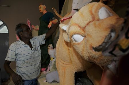  An artisan fixes the idols at a temple one day ahead of Durga Puja, the biggest religious festival of Hindus, in Dhaka, capital of Bangladesh, on Sept. 23, 2009. The five-day festival will start from Thursday. (Xinhua/Qamruzzaman)