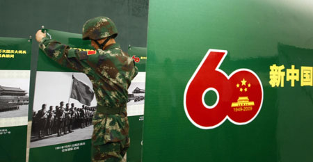A soldier displays photos at the Parade Photo Exhibition in Beijing, China, Sept. 24, 2009. A photo exhibition recording previous parades after the founding of the People's Republic of China in 1949 was held at Parade Village where all the soldiers who will join the parade on Oct.1 take part in practices. (Xinhua/Liu Bin)