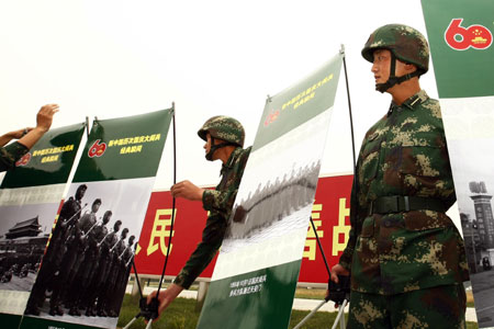 Soldiers display photos at the Parade Photo Exhibition in Beijing, China, Sept. 24, 2009. A photo exhibition recording previous parades after the founding of the People's Republic of China in 1949 was held at Parade Village where all the soldiers who will join the parade on Oct.1 take part in practices. (Xinhua/Liu Bin) 