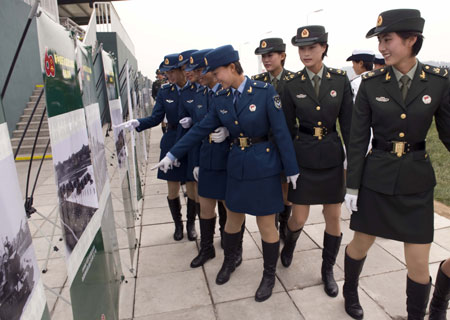 Soldiers watch photos at the Parade Photo Exhibition in Beijing, China, Sept. 24, 2009. A photo exhibition recording previous parades after the founding of the People's Republic of China in 1949 was held at Parade Village where all the soldiers who will join the parade on Oct.1 take part in practices. (Xinhua/Liu Jie)