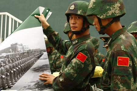 Soldiers display photos at the Parade Photo Exhibition in Beijing, China, Sept. 24, 2009. A photo exhibition recording previous parades after the founding of the People's Republic of China in 1949 was held at Parade Village where all the soldiers who will join the parade on Oct.1 take part in practices. (Xinhua/Liu Bin) 