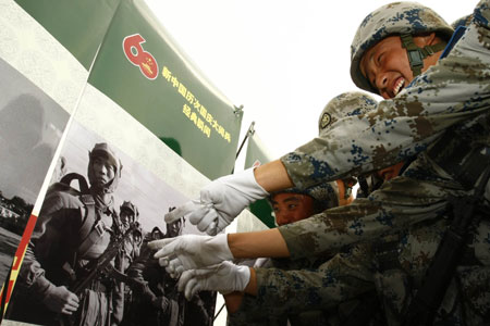 Soldiers watch photos at the Parade Photo Exhibition in Beijing, China, Sept. 24, 2009. A photo exhibition recording previous parades after the founding of the People's Republic of China in 1949 was held at Parade Village where all the soldiers who will join the parade on Oct.1 take part in practices. (Xinhua/Liu Bin) 