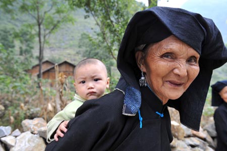 An old woman of Dark Cloth Zhuang carries her grandson on the back in Napo county, southwest China's Guangxi Zhuang Autonomous Region, Sept. 23, 2009. Peolpe of Dark Cloth Zhuang, which is a special branch of the Zhuang ethnic group, adore black colour and have preserved many ancient habits. With the help of the government, the labor and living conditions of the 52,000 Dark Cloth Zhunag people have been improved and their particular life remained that attracks many tourists both domestically and internationally.(Xinhua/Liu Guangming) 